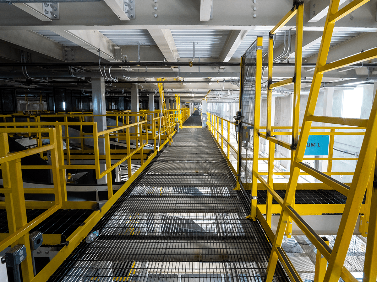 Butler compatible industrial catwalk with open-bar grating floor modular steel guardrails and hanger rod mounting system for metal building interior access