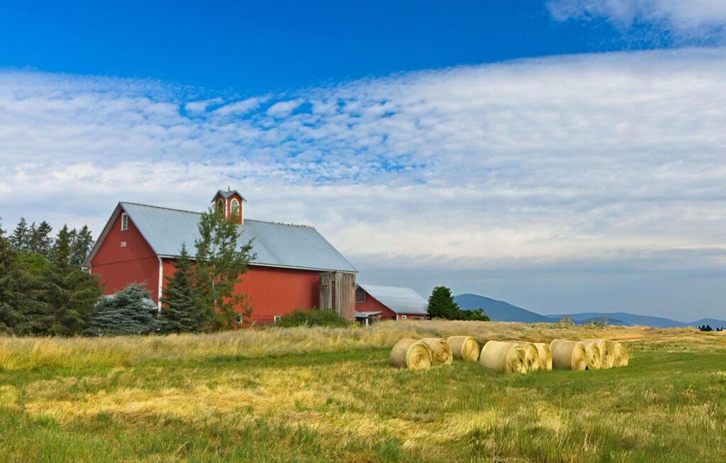 Butler Picturesque red barn with hay bales in rural landscape